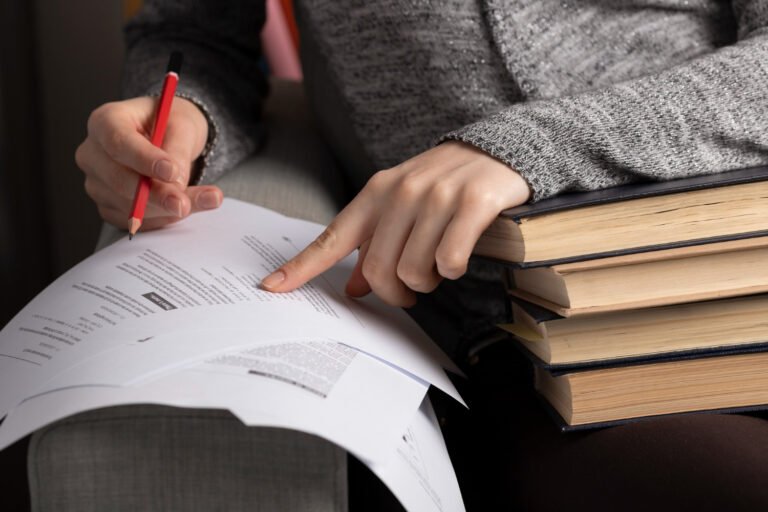 Person studying documents and books to prepare for the Indian Patent Agent examination.